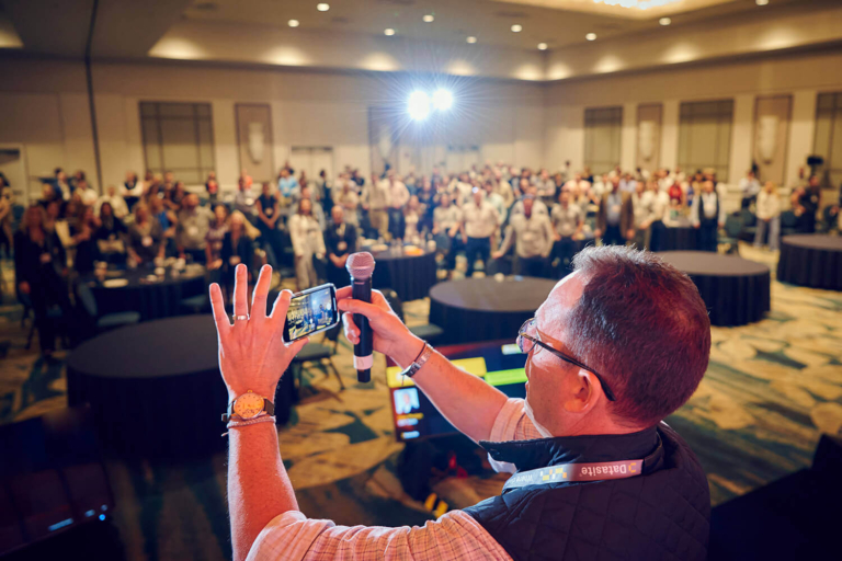 Attendee taking a photo with his phone during a corporate conference