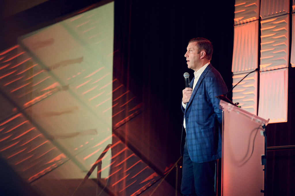 Keynote speaker with a microphone on stage at a corporate conference in Orlando