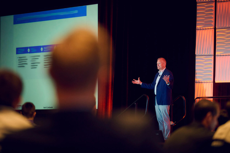 Presenter speaking next to the presentation screen at a corporate event