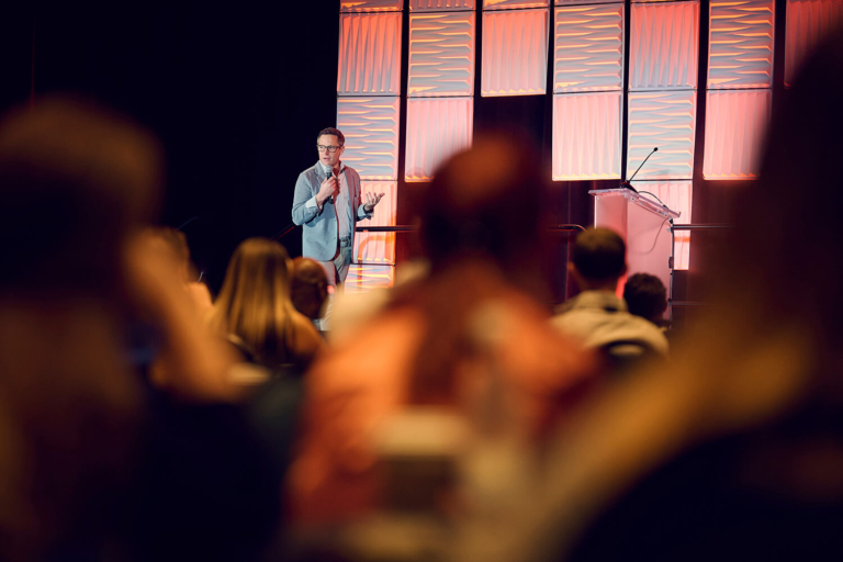 Speaker on stage seen through the audience at a corporate event