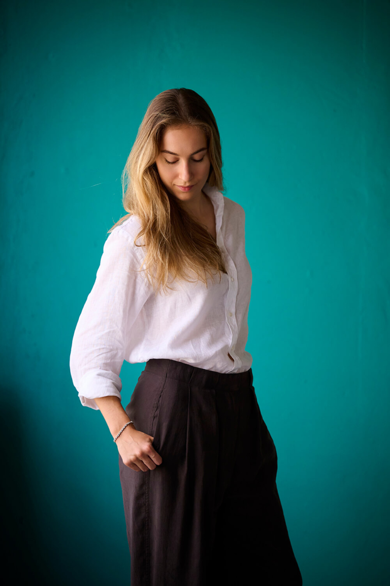 Relaxed personal branding portrait of a woman in motion against a teal backdrop