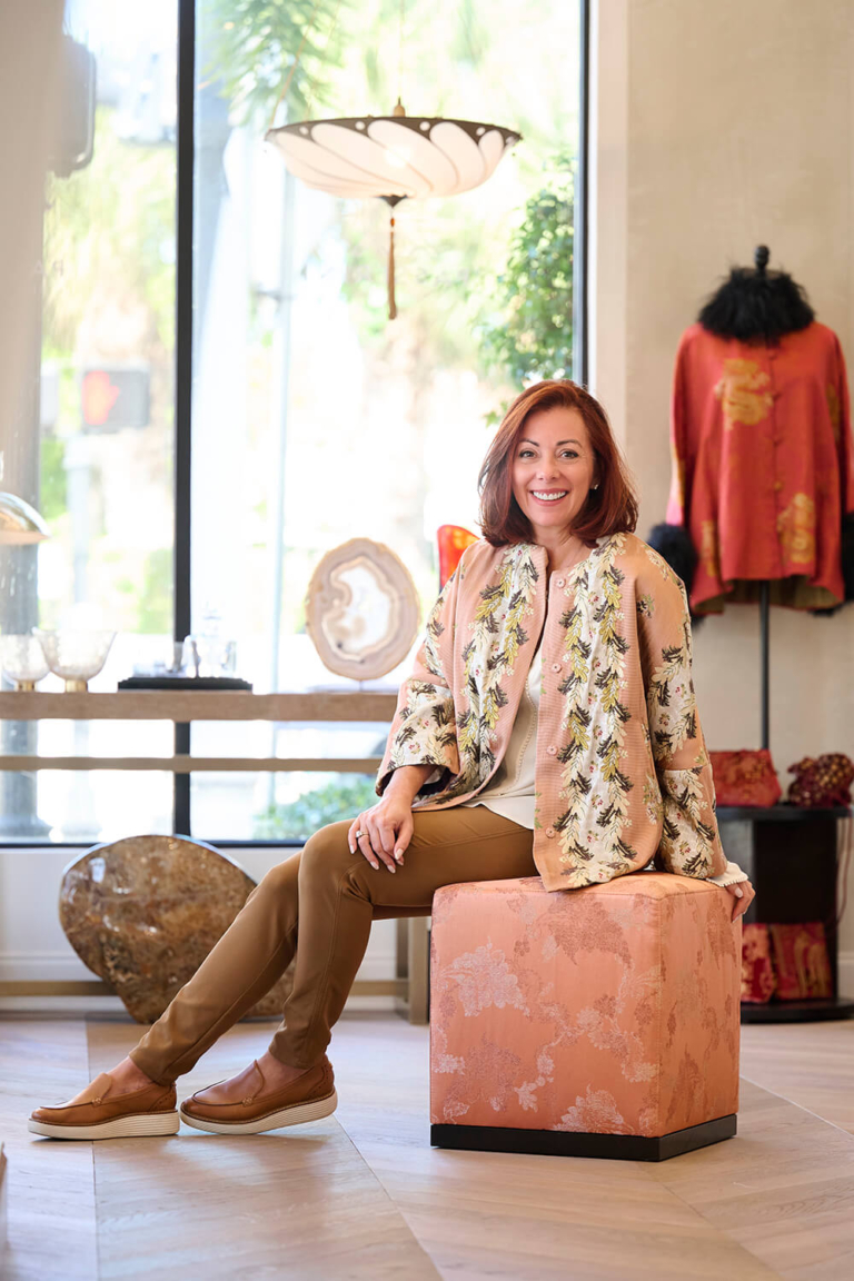 Personal branding portrait of a business owner seated in her Palm Beach store
